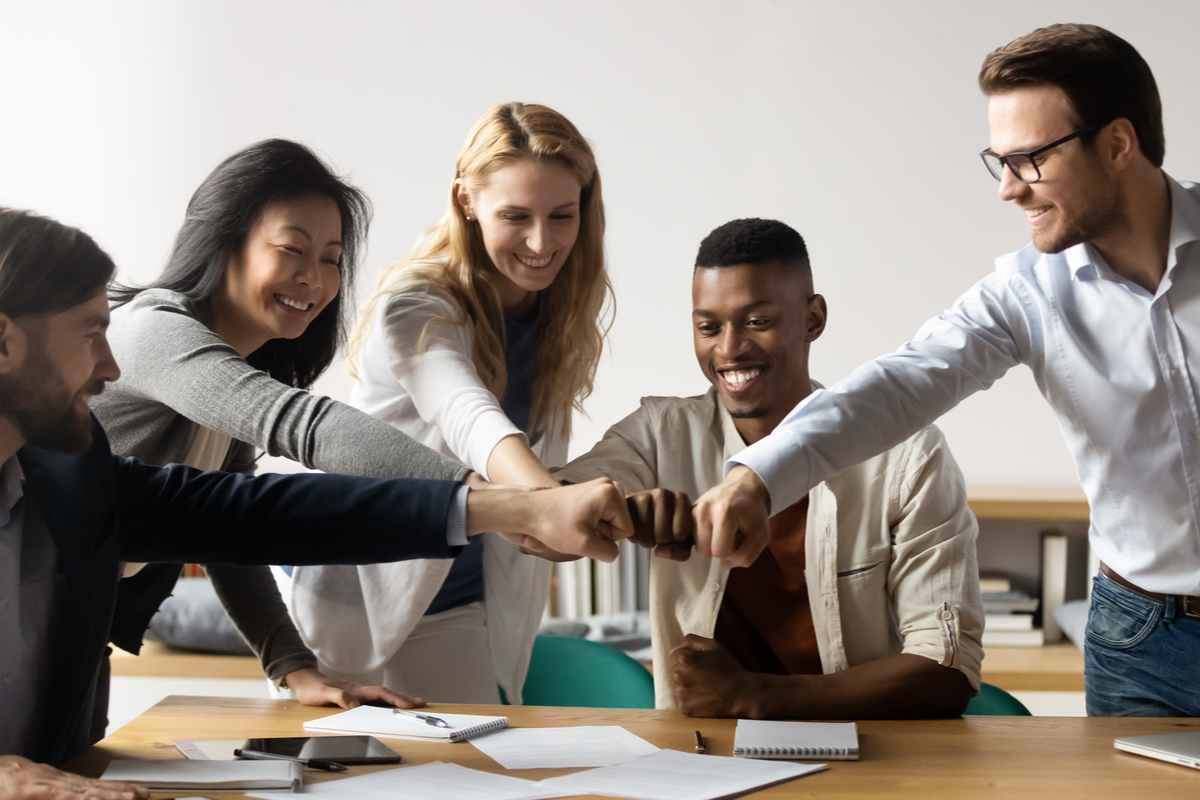 Diverse group of young professionals giving a team fist-bump as they collaborate.